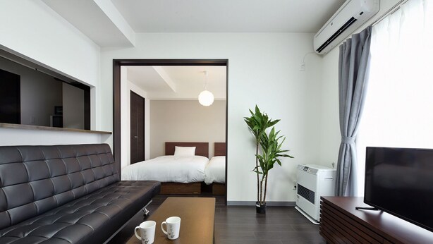 Habitació d'hotel moderna amb sofà, llit, taula de cafè, televisió i aire condicionat.