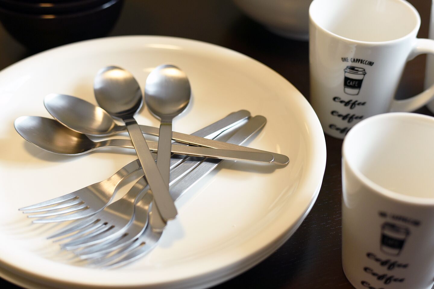 A white plate with a fork, spoon, and knife arranged on it.