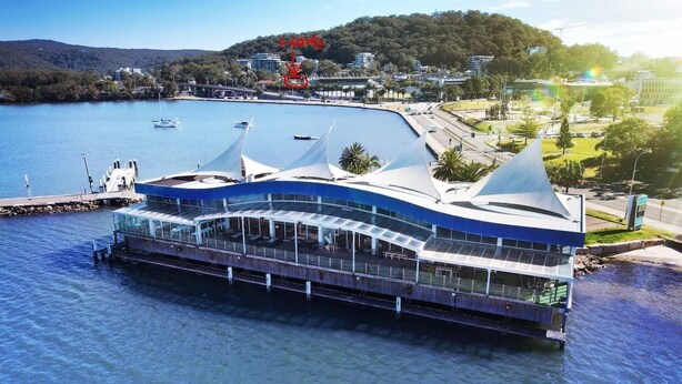 Ein Gebäude am Wasser mit einer gewölbten Dachform und großen Fenstern, wahrscheinlich ein Hotel oder ein Restaurant.
