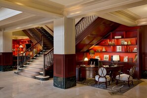 A grand lobby with a marble floor, a staircase with a wrought iron railing, and a desk area with chairs and a lamp. - Discover Austin's History! Enjoy Pet-Friendly Stay! Swimming Pool Available! (Austin)