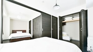 Een moderne hotelkamer met een groot bed, een donkere houten garderobe en een witte plafondlamp.