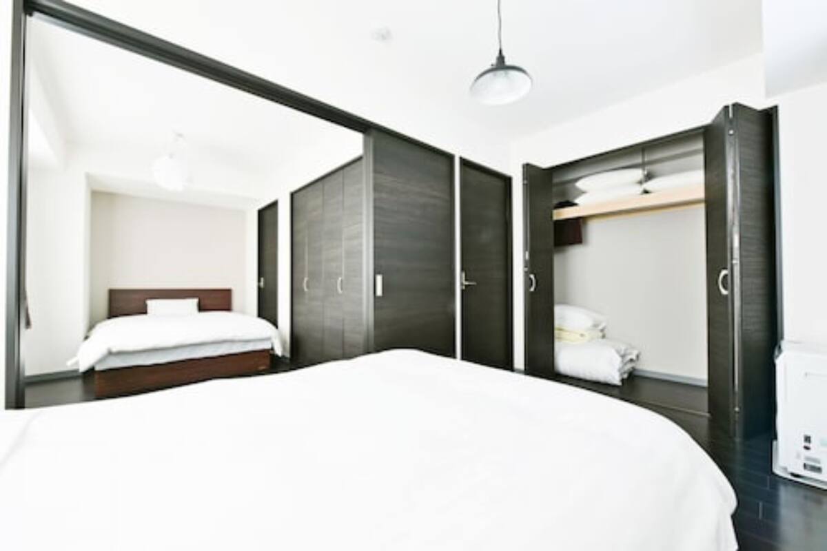 Ein modernes Hotelzimmer mit einem großen Bett, einem dunklen Holzschrank und einer weißen Deckenleuchte.