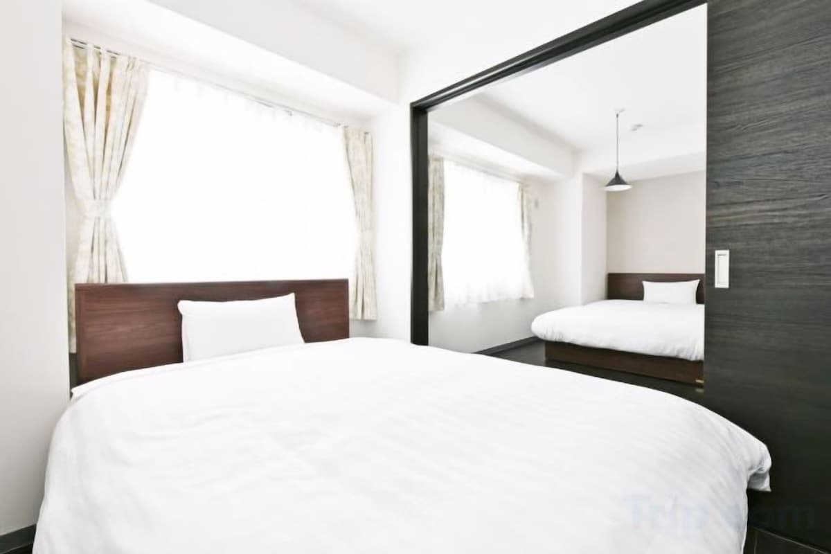 A hotel room with a large bed, a wooden headboard, a mirror, and a window with curtains.