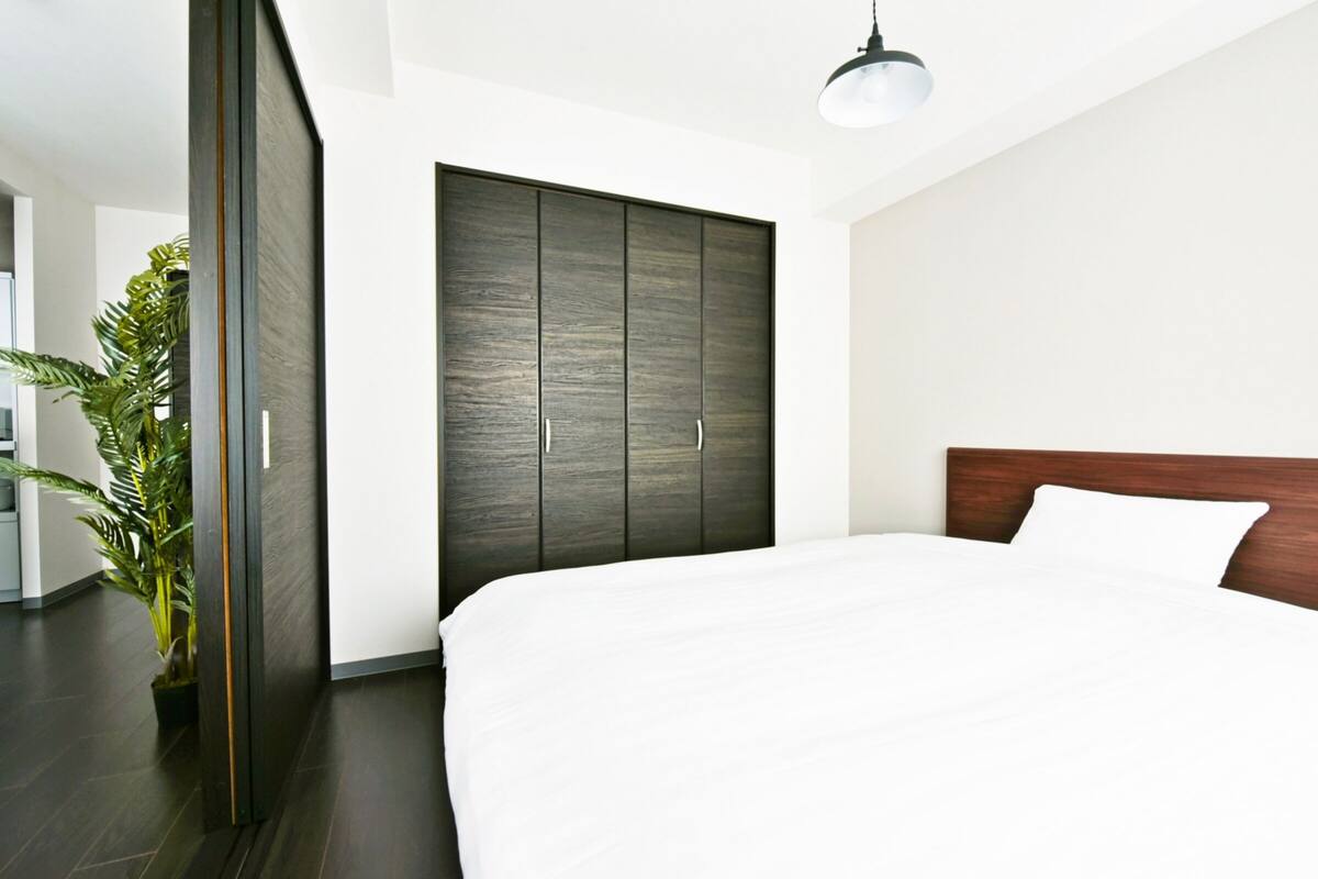 Ein modernes Schlafzimmer mit einem großen Bett, einem dunklen Holzschrank und einem Blumentopf.