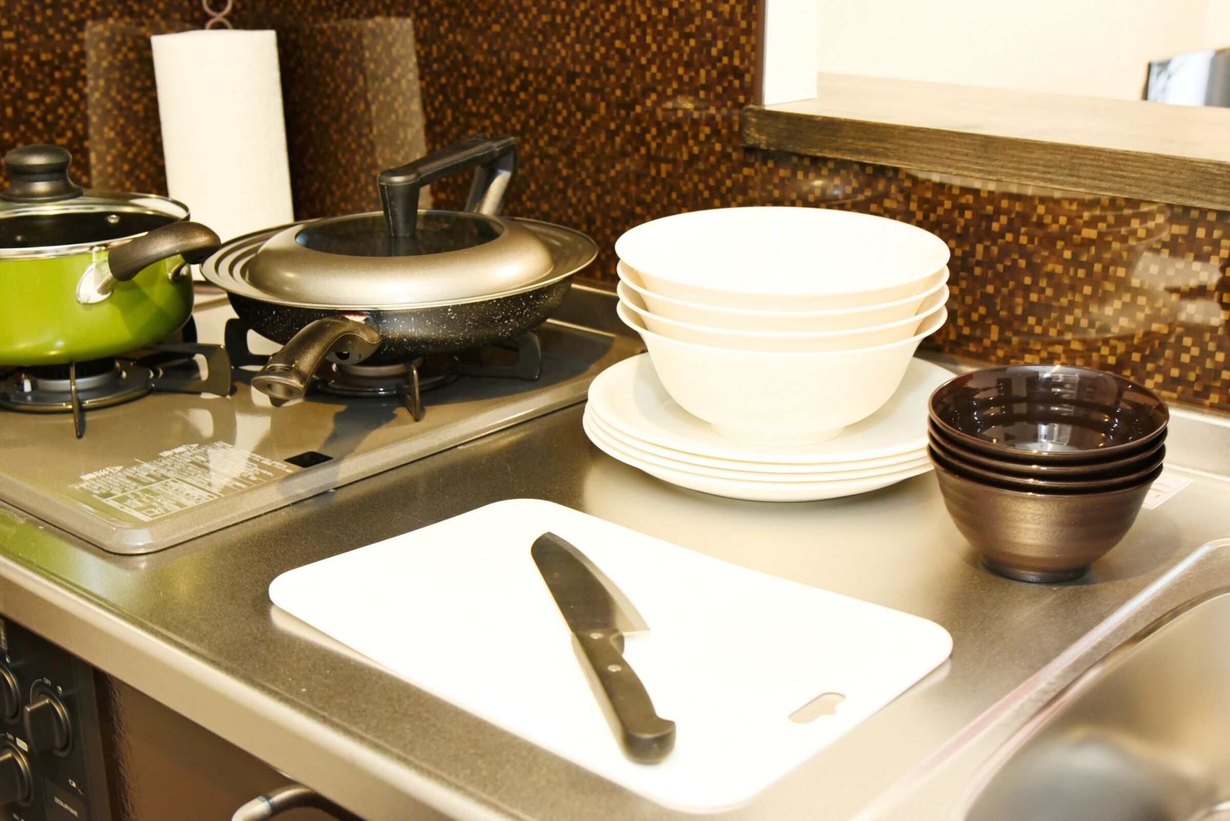 A kitchen with a stove, pots, a cutting board, and stacked bowls.