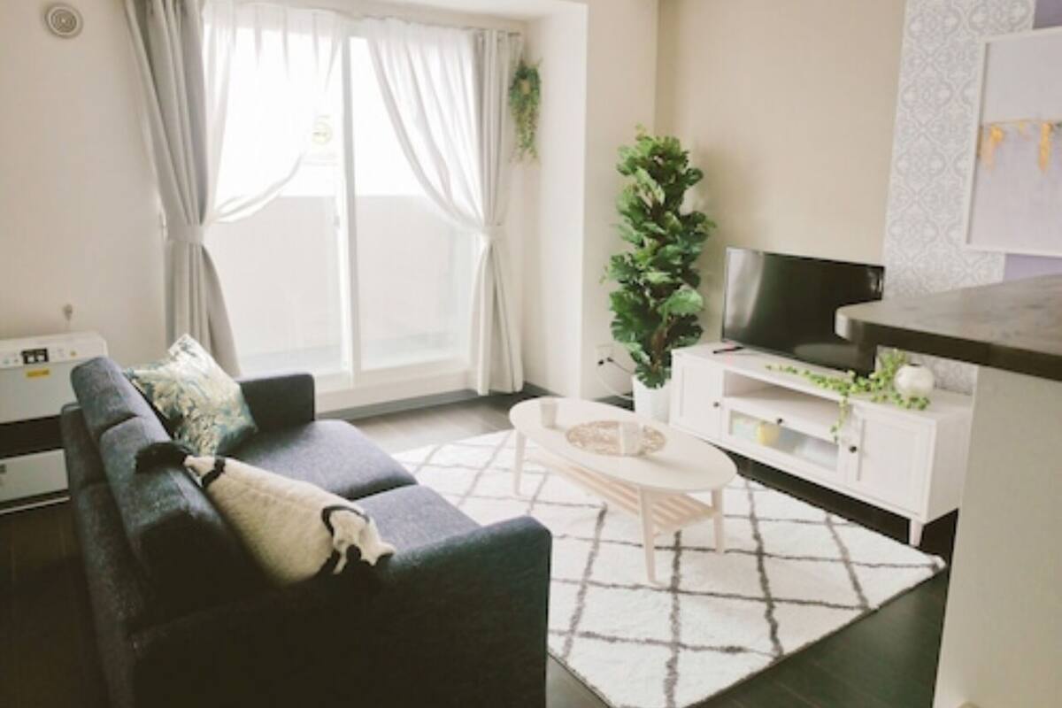 Ein Wohnzimmer mit einer Couch, einem Couchtisch, einem Fernseher und einer Pflanze.