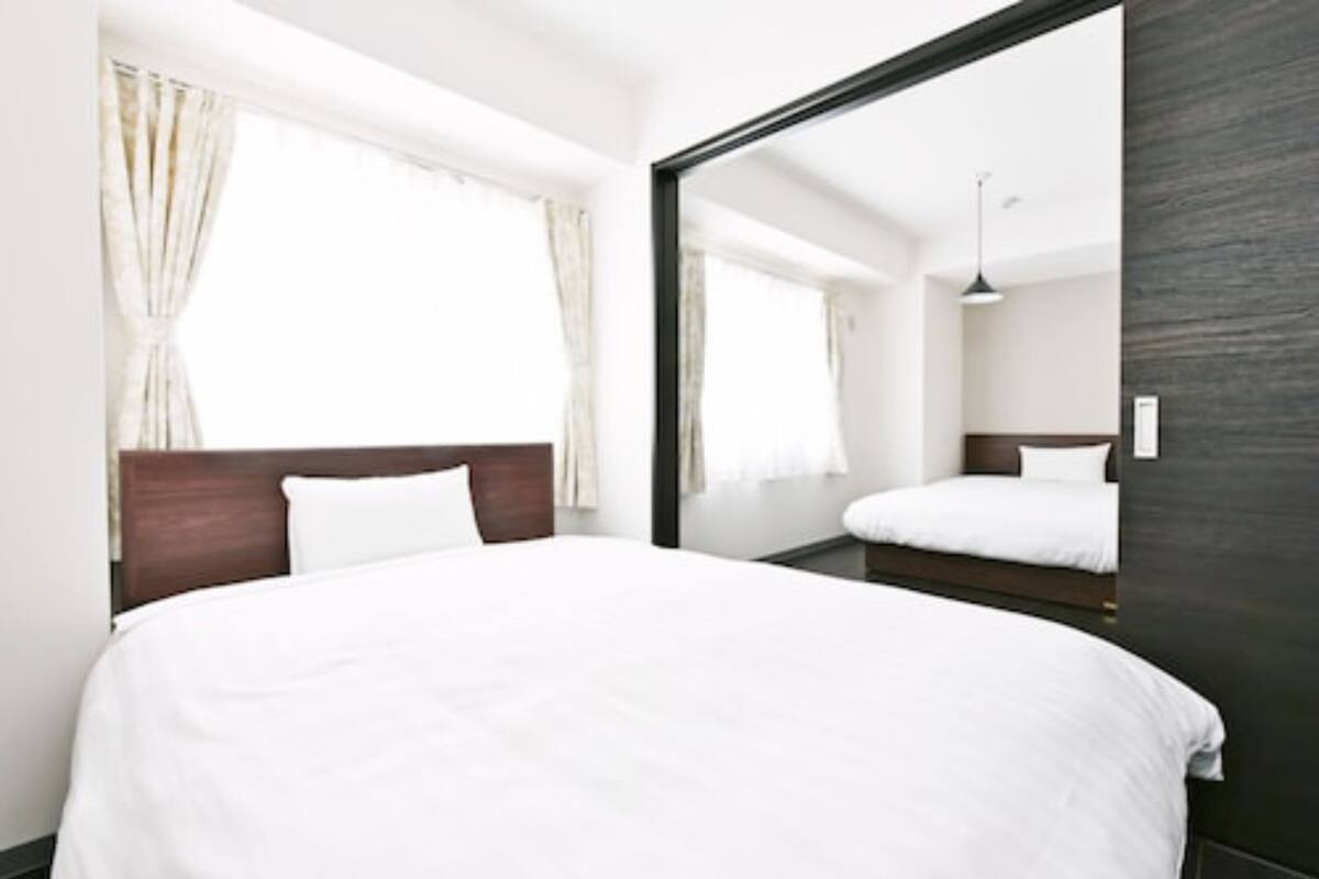 Ein Hotelzimmer mit einem großen Bett, einem hölzernen Kopfteil und einem Spiegel, der den Raum widerspiegelt.