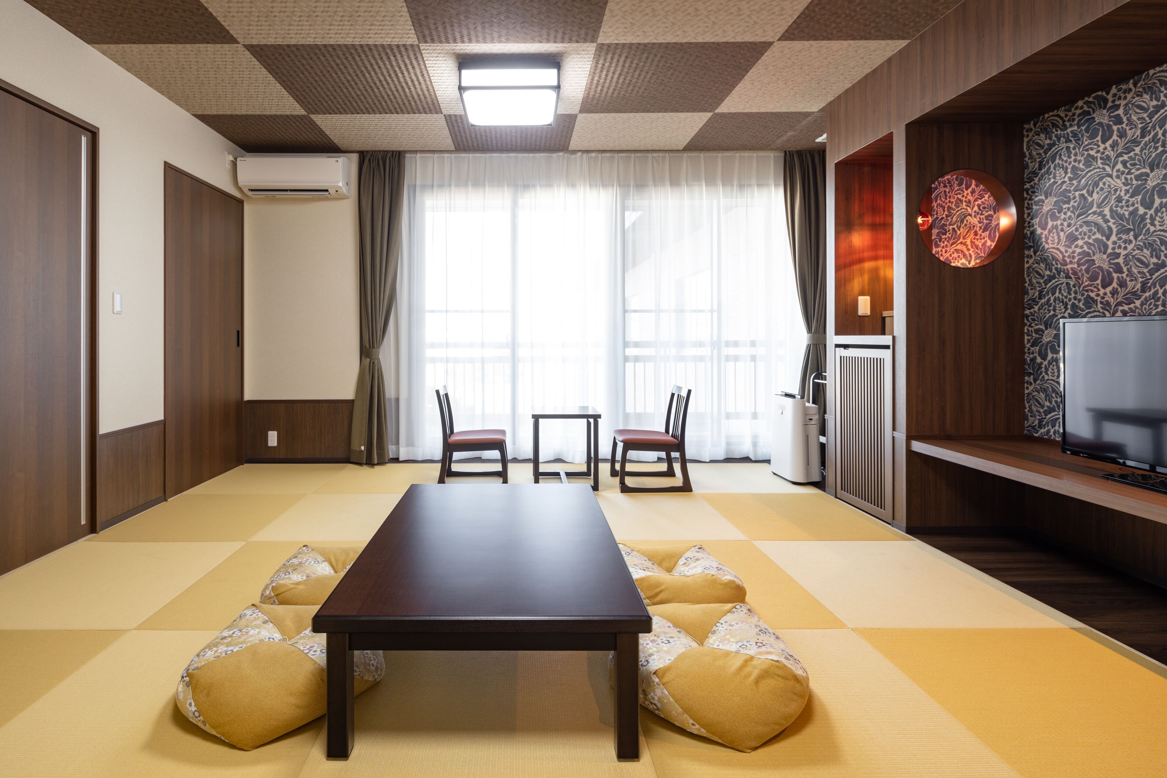Ein traditioneller japanischer Raum mit Tatami-Boden, einem niedrigen Tisch und einem Fernseher auf einem Holzständer.