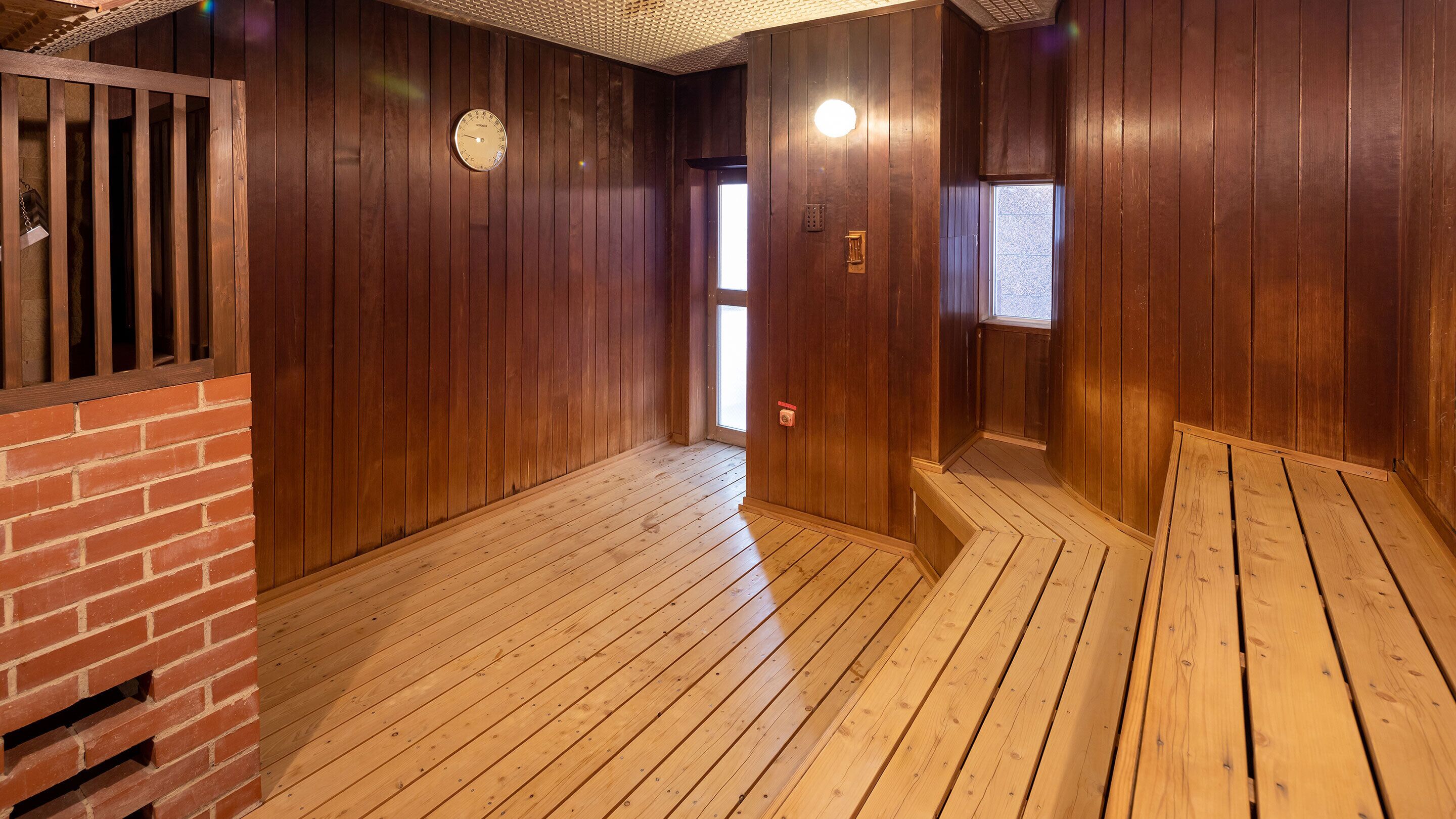Une pièce aux murs et au plancher en bois, avec un mur en briques d’un côté et une fenêtre qui laisse entrer la lumière naturelle.