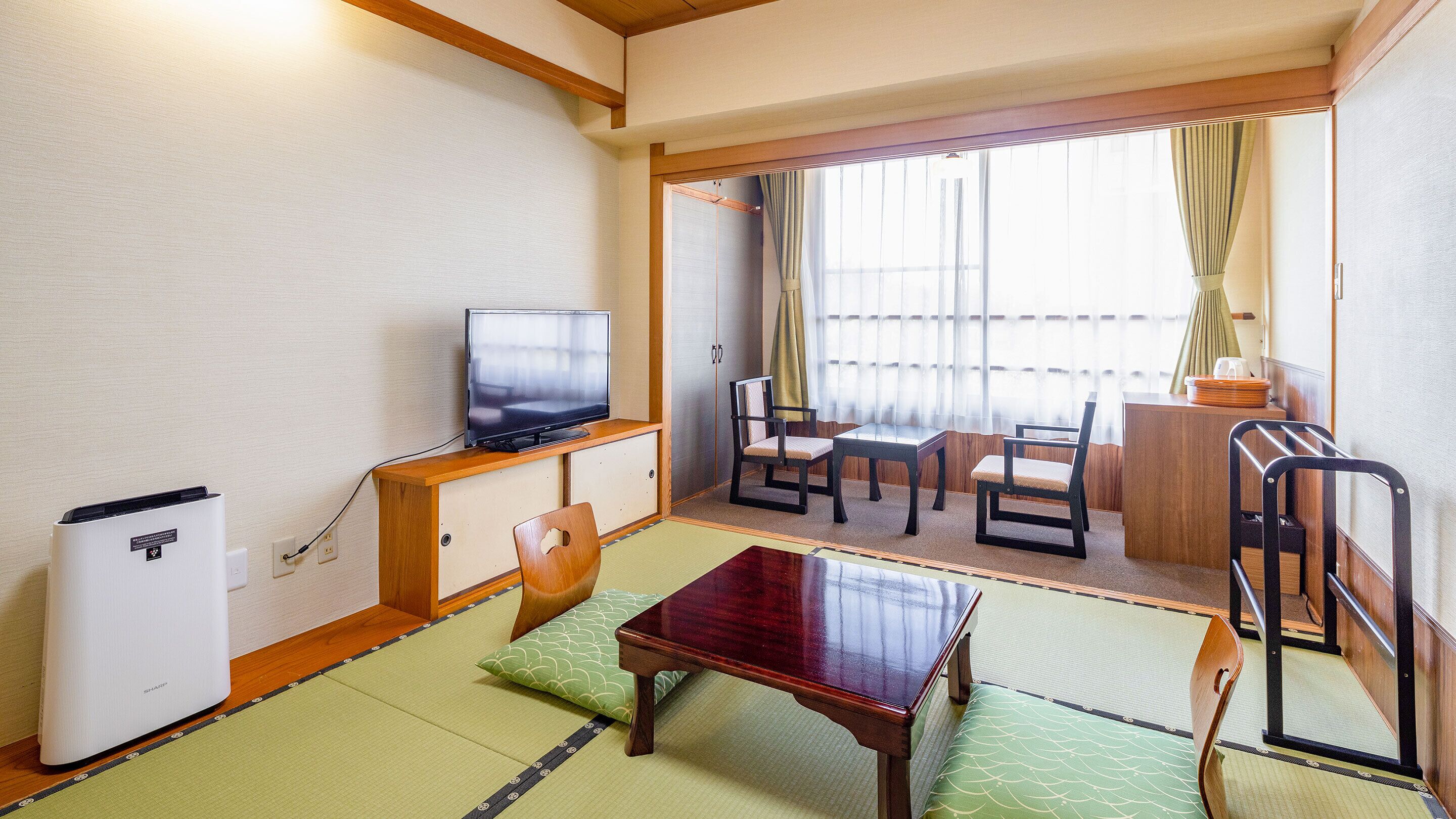 Ein traditioneller japanischer Raum mit Tatami-Böden, einem Fernseher, einem Holztisch und einer Couch.