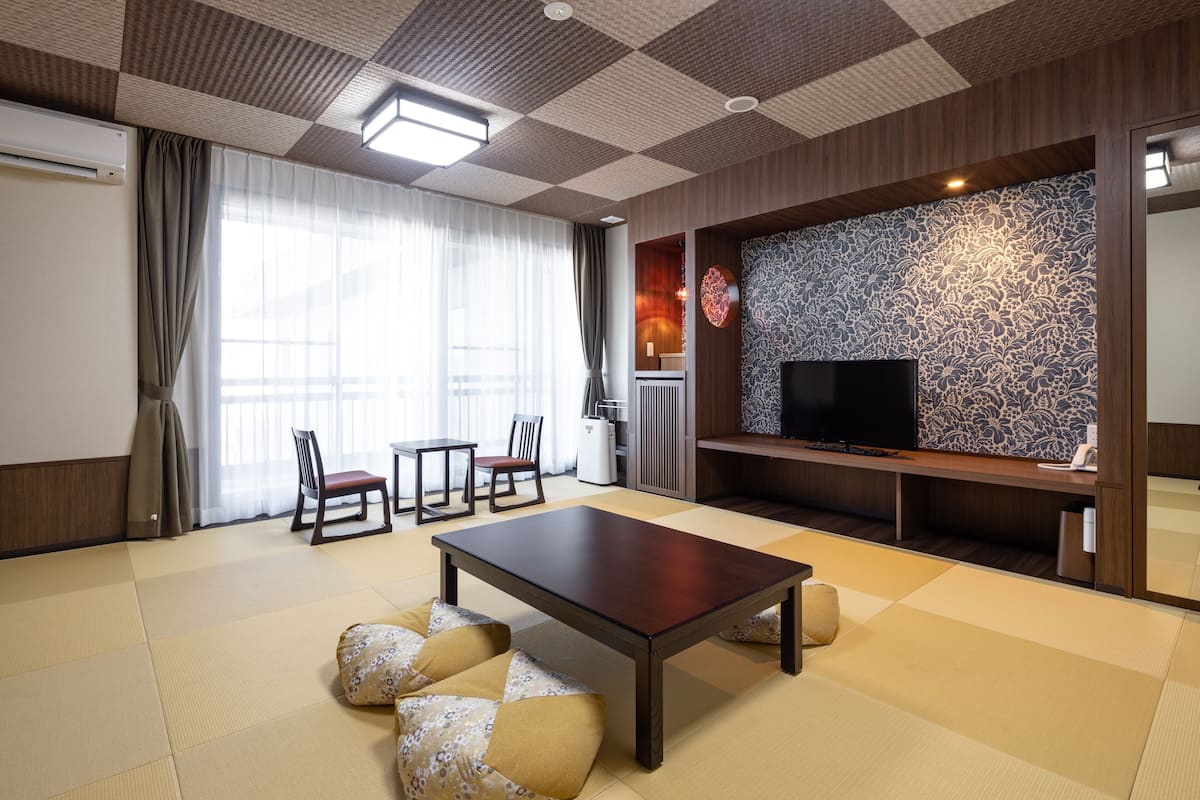 A modern living room with tatami flooring, a wooden coffee table, and a flat-screen TV.