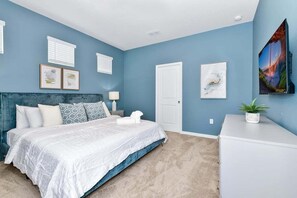 Een slaapkamer met een bed, nachtkastje, dressoir en kunst aan de wanden.