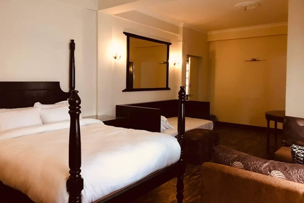 Habitación de hotel con dos camas, un espejo grande y una mesita.