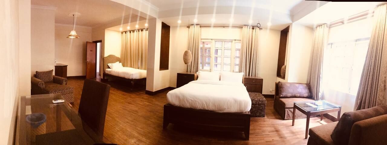 A hotel room with a large bed, two armchairs, a small table, and a sofa.