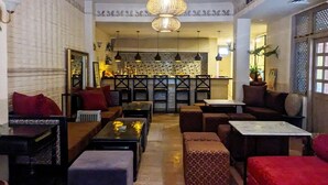 A spacious living area with a high ceiling, multiple seating arrangements, and a kitchen in the background. - Courtyard Pujan Hotel (Kathmandu)