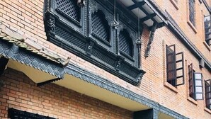 A traditional building with ornate black window frames and a brick facade. - Courtyard Pujan Hotel (Kathmandu)