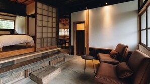 Um quarto em estilo japonês tradicional, com piso de tatame, cama de madeira baixa, área de estar acolchoada e porta de papel deslizante shoji.