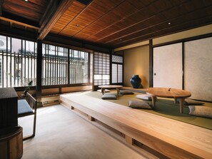 A traditional Japanese room with tatami flooring, low wooden tables, and a large vase. -  RITA IZUMO HIRATA (Izumo)