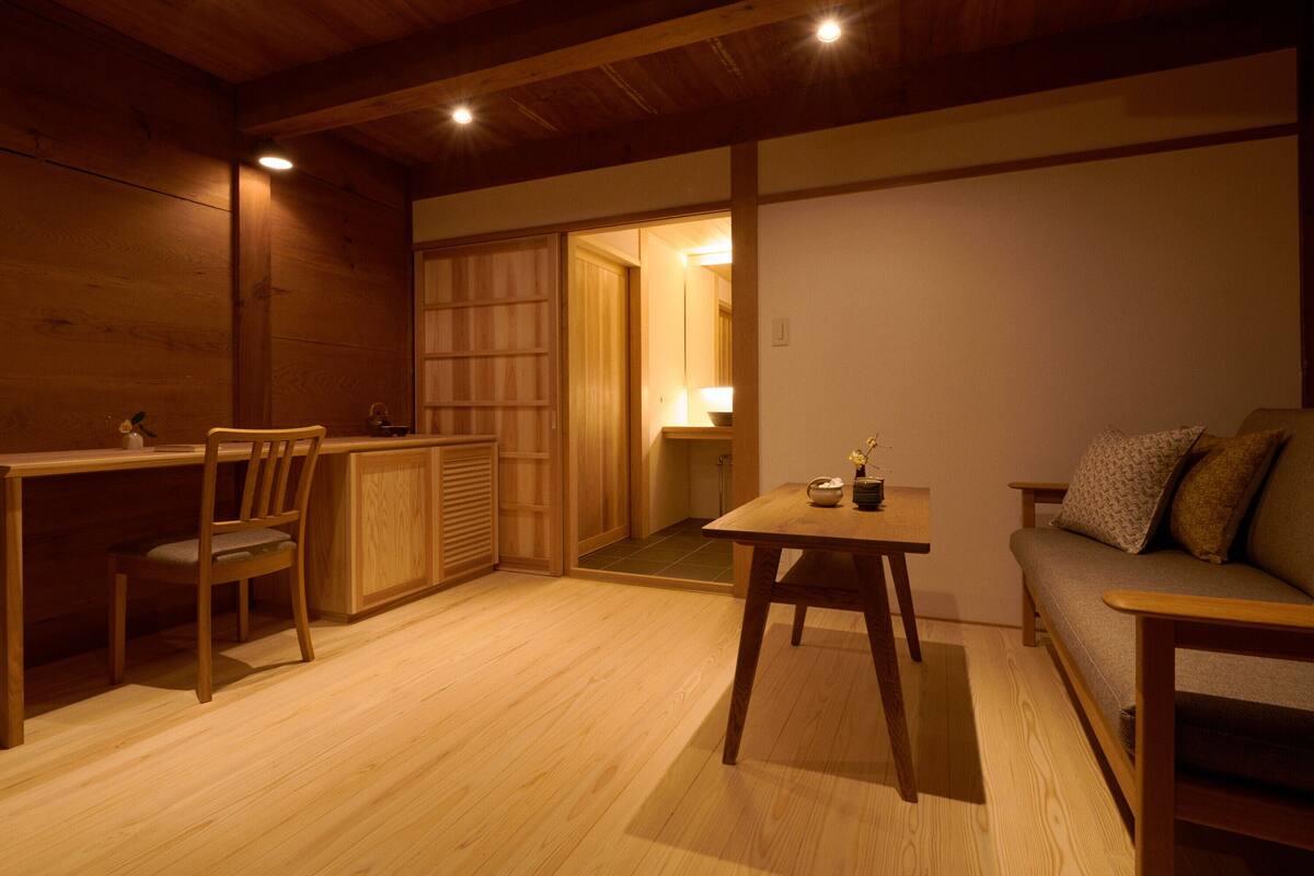 Un intérieur en bois comprenant une table à manger, des chaises, un canapé et une petite table sur laquelle est posé un vase.