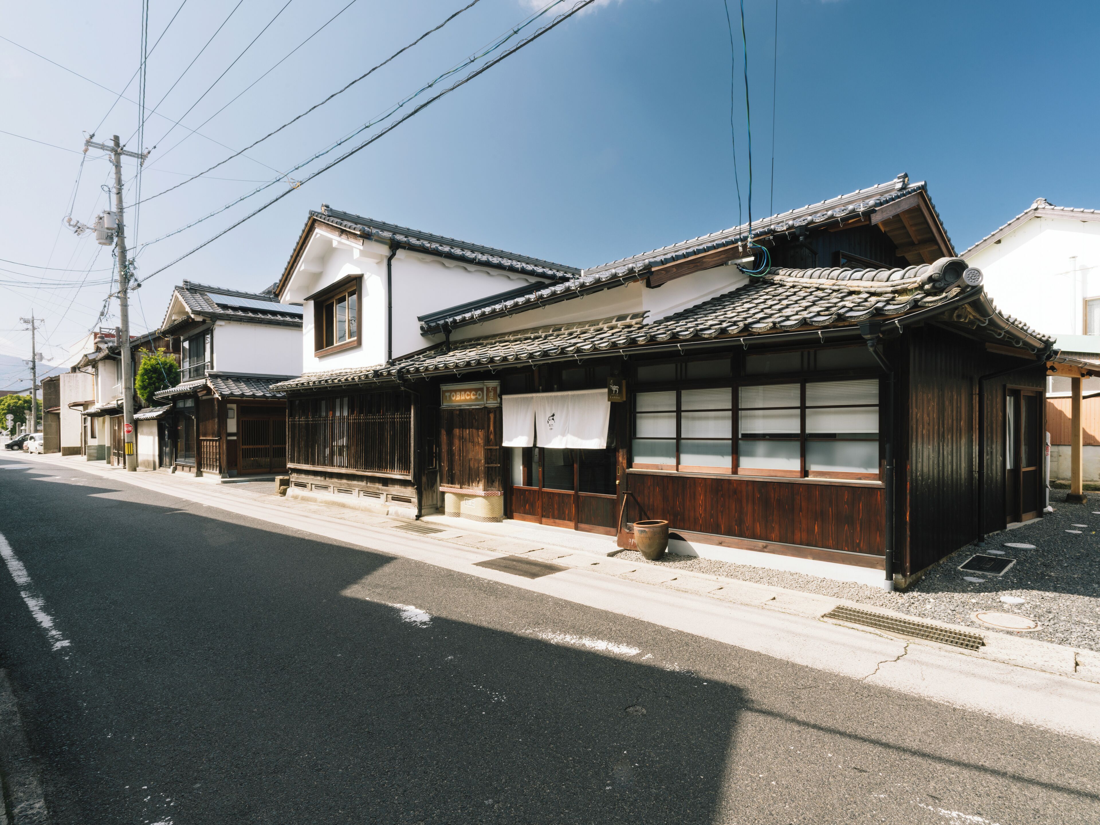 Un edificio japonés tradicional con tejado de tejas, fachada de madera y un letrero que indica una tienda de tabaco.