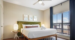 Relax in a stylish room with a large bed, bedside table, and window with blinds.