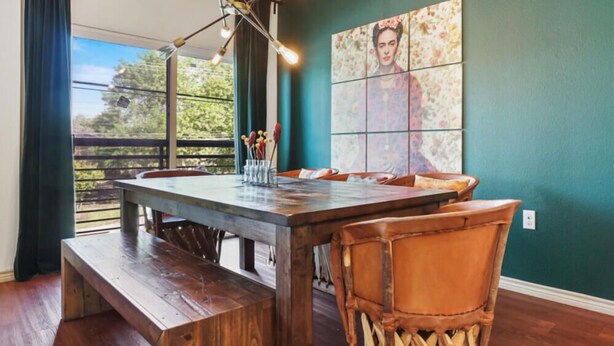 A dining area with a wooden table and bench, a modern chandelier, and a large floral artwork on the wall. - TNC #205 xxxxxxxxxxx (Austin)