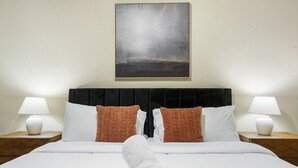 A hotel room with a large bed, two pillows, a headboard, two bedside lamps, and a painting on the wall. - TNC #206 xxxxxxxxxxx (Austin)