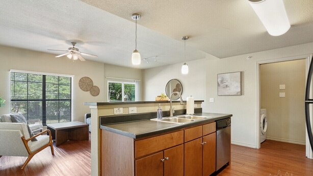 A modern kitchen with wooden cabinets, a central island, a dishwasher, and a ceiling fan. - TNC #206 xxxxxxxxxxx (Austin)