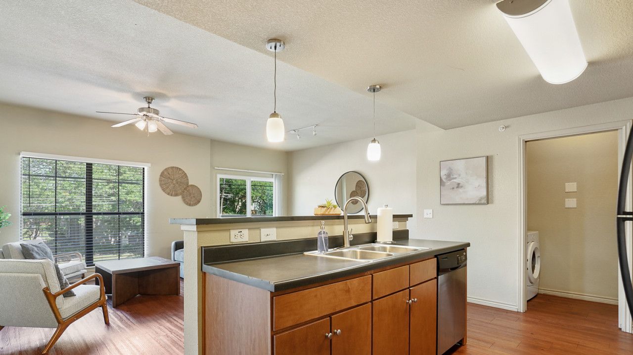 A modern kitchen with wooden cabinets, a central island, a dishwasher, and a ceiling fan.