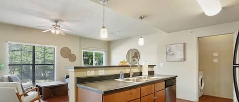 A modern kitchen with wooden cabinets, a central island, a dishwasher, and a ceiling fan.
