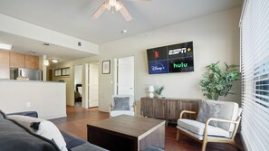 A modern living room with a flat-screen TV displaying various streaming services, a wooden coffee table, and comfortable seating.