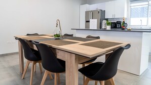 A modern kitchen with a central island, black chairs, and a wooden dining table. - Modern 3BR Home with Own Private Pool - Centrally Located - Quiet Neighborhood (Cole bay)
