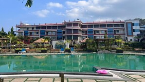A hotel with a swimming pool, multiple balconies, and a garden area. - AT Hotels & Resorts (Port Blair)