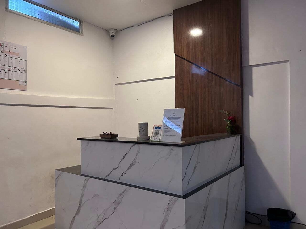 A reception desk with a marble top, a wooden panel, and a sign.
