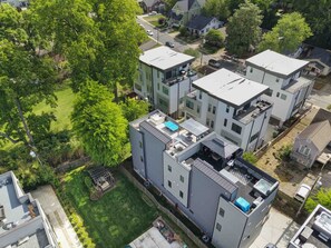 Un moderno edificio residencial con varias unidades, un jardín en la azotea y un césped bien cuidado.