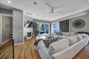 Un salon moderne avec un grand canapé, un téléviseur à écran plat et un ventilateur de plafond.