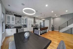 A modern kitchen with white cabinets, a black dining table, and a coffee bar. - 906 Westbrook B  · City Views RoofTop Hot Tub & Short Walk to Stadium (Charlotte)