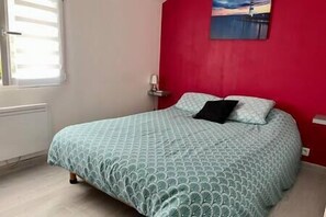Une chambre à coucher avec un lit, un mur rouge et un tableau.
