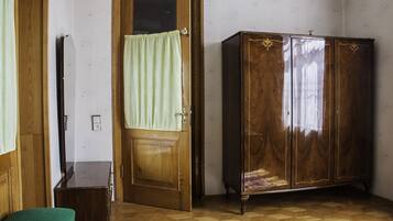 Una habitación con un armario de madera, una silla verde y una puerta de madera con cortina.