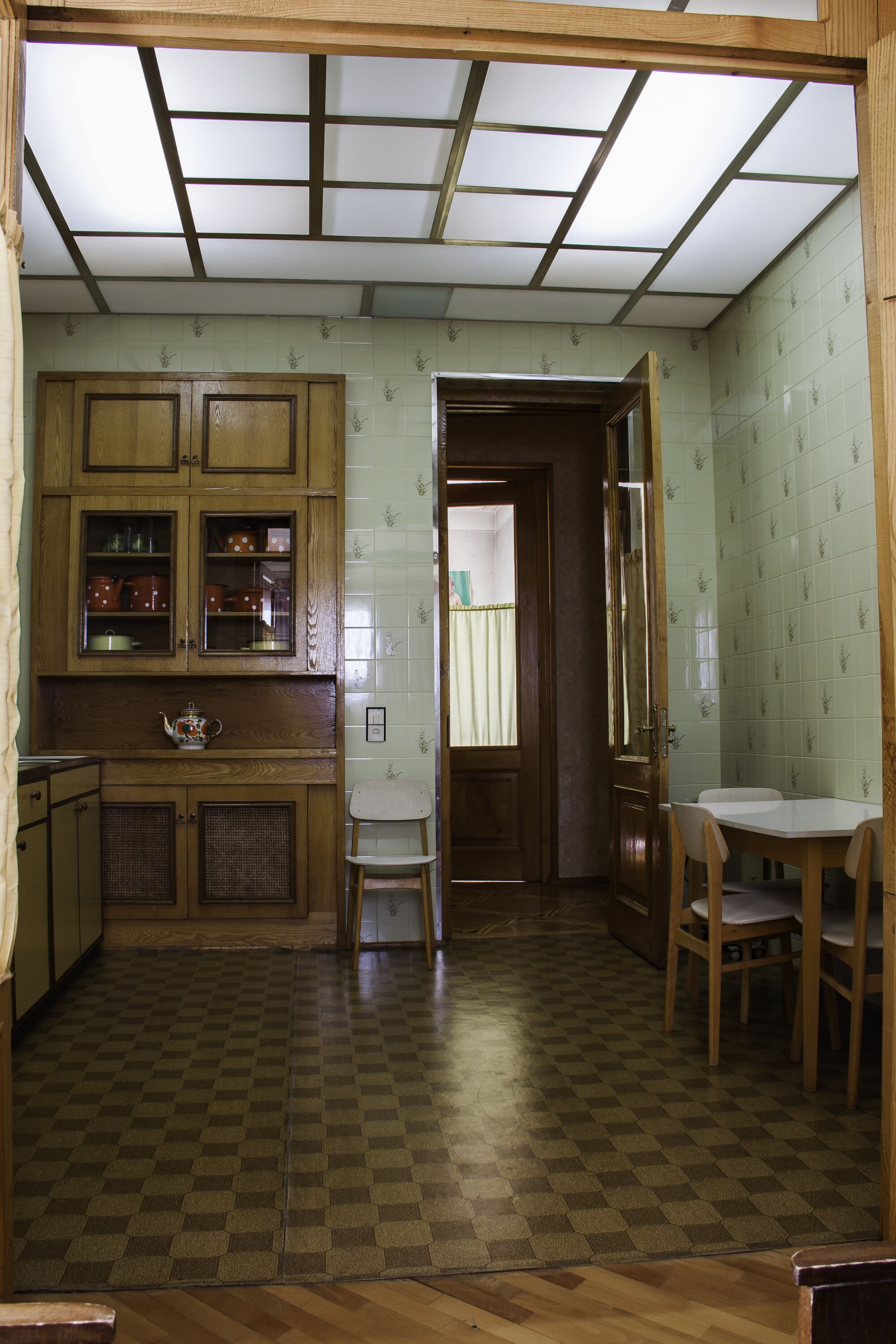 Una cocina con armarios de madera, piso a cuadros y una ventana con cortinas.