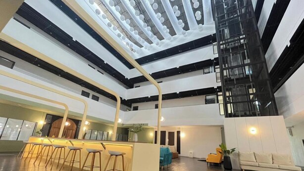 Un vestíbulo amplio con una zona de bar central, una escalera y un área de descanso con sofá y sillones.