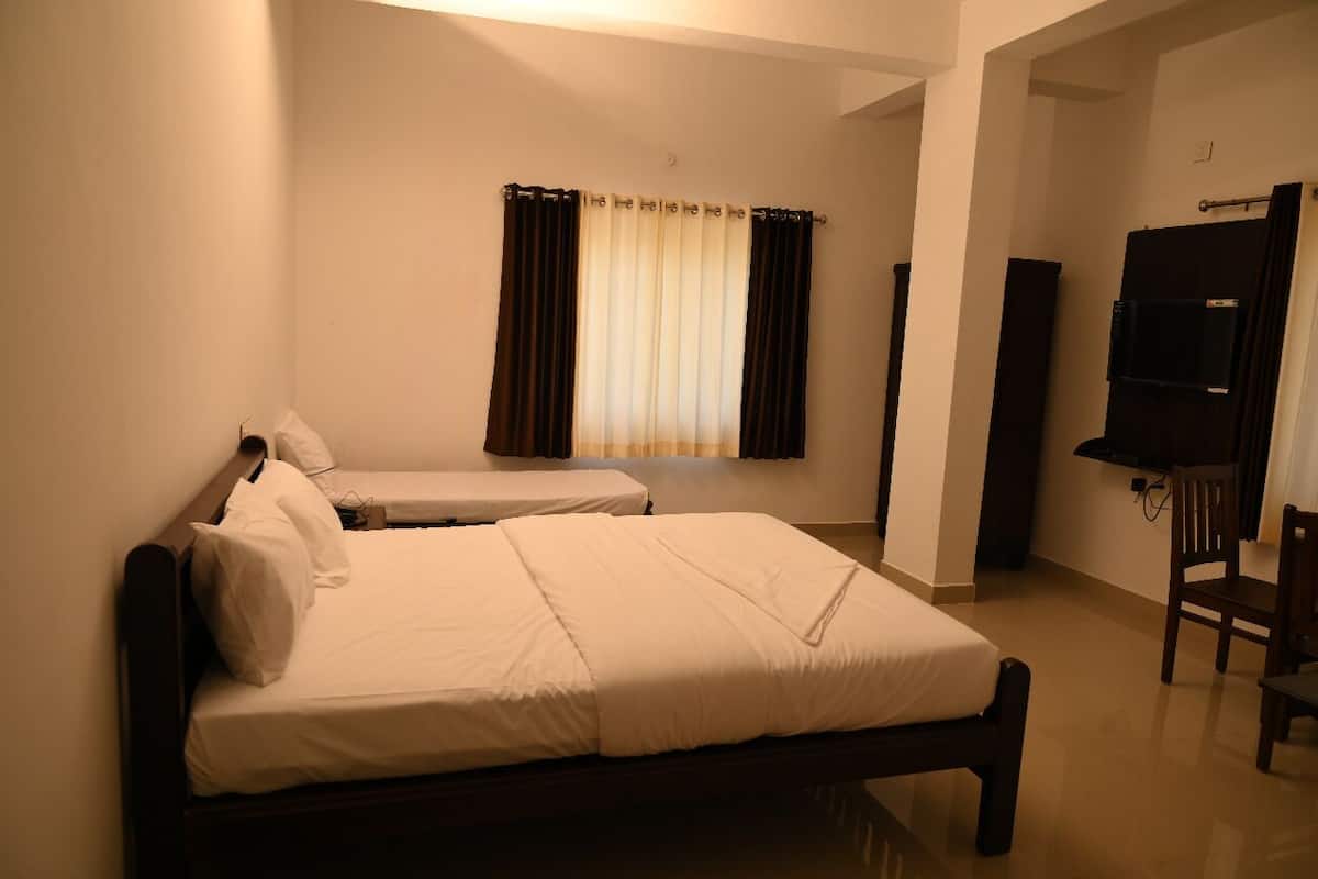 A hotel room with two single beds, a TV, and a chair.