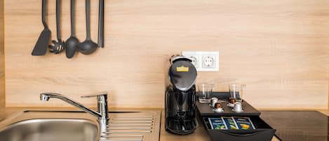 Una cocina moderna con un lavamanos de acero inoxidable, una cafetera y una bandeja con cápsulas de café.