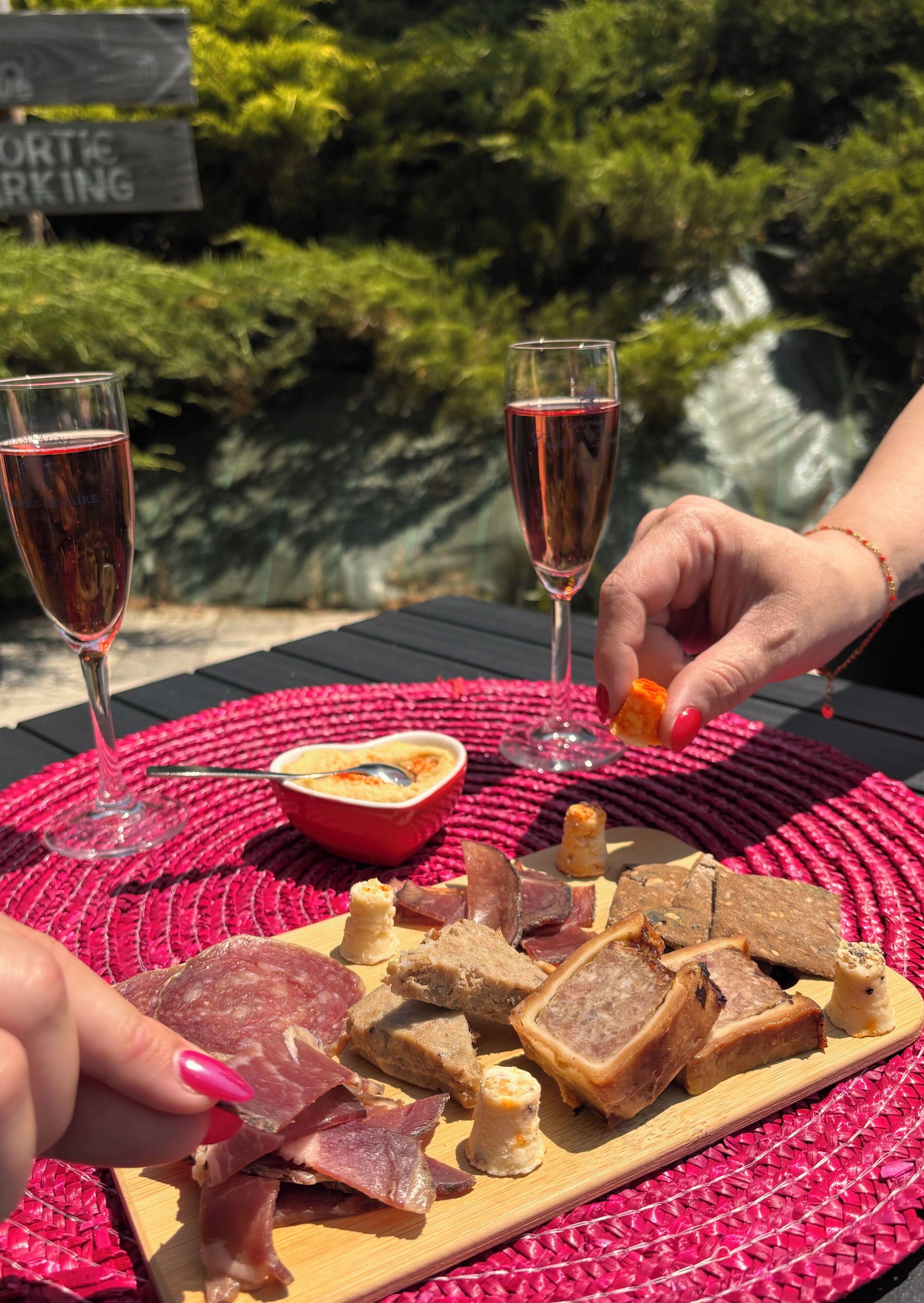 A table with a charcuterie board, two glasses of red wine, and a bowl of soup.
