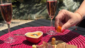 A table with a charcuterie board, two glasses of red wine, and a bowl of soup.