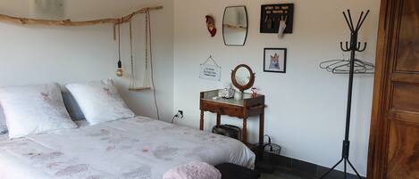 A bedroom with a bed, a wooden dresser, a mirror, and a coat rack.
