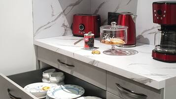 A modern kitchen with a microwave, coffee maker, and a drawer with stacked dishes.