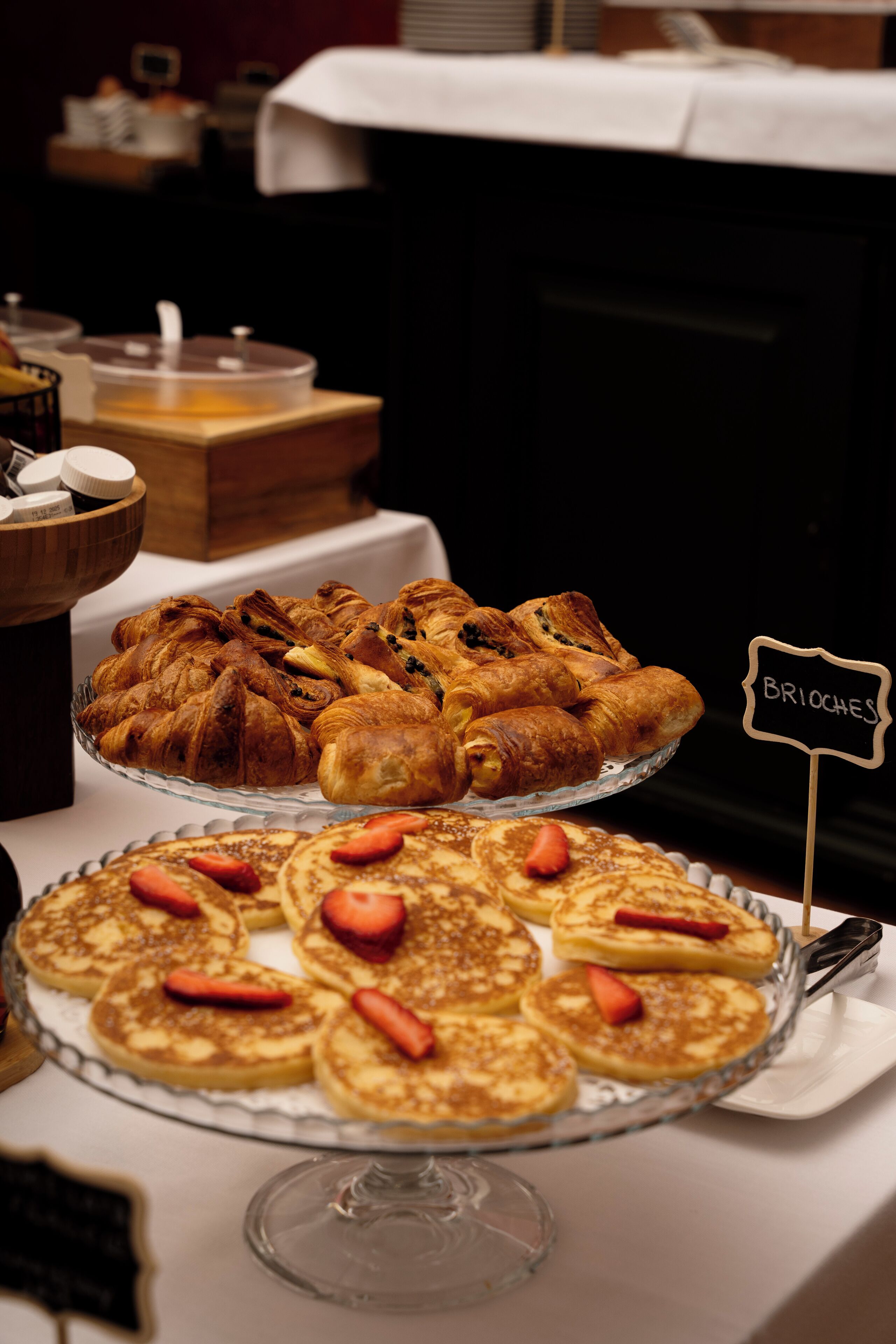Un buffet proposant diverses pâtisseries et crêpes, avec un panneau indiquant « BRIOCHES ».