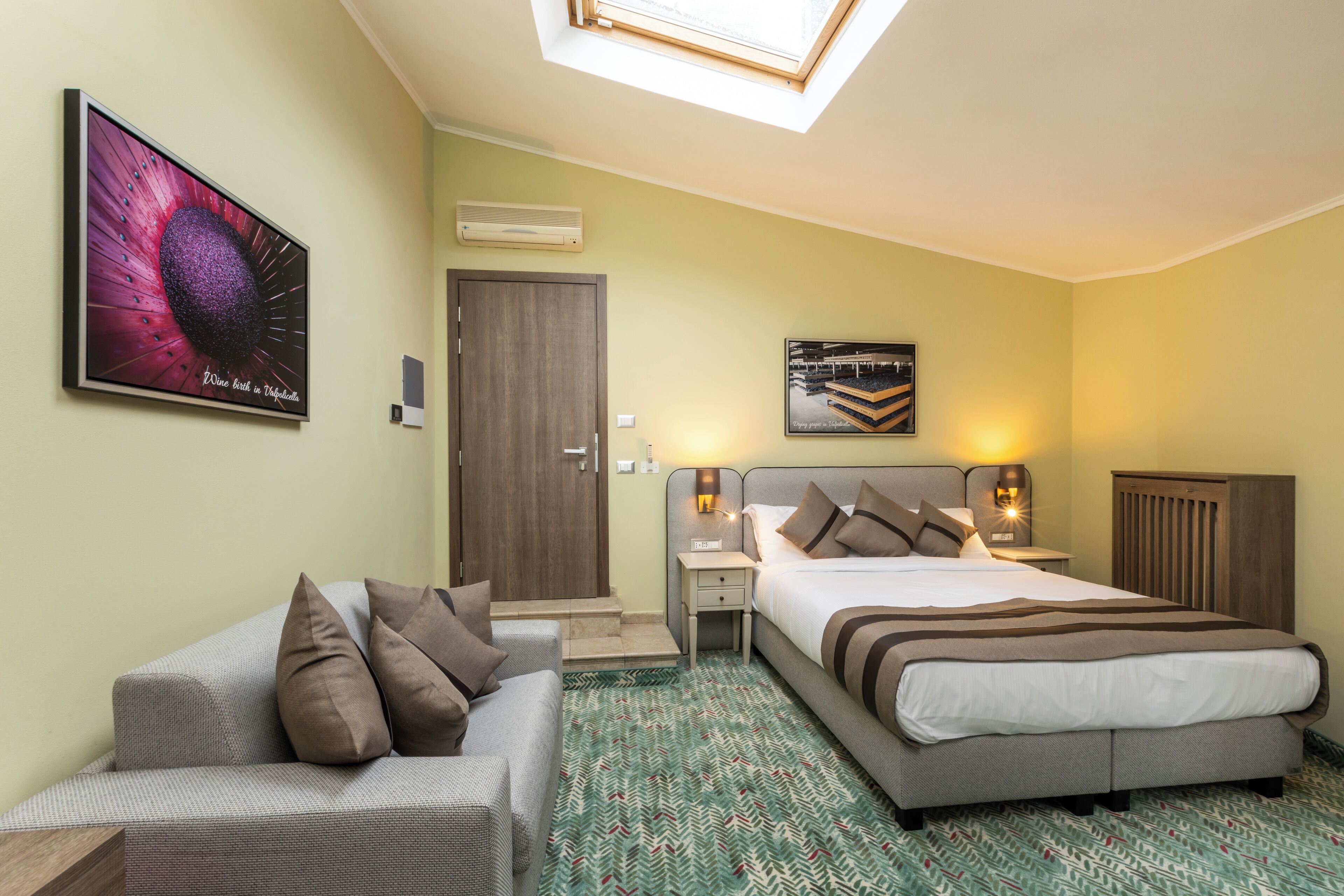 A hotel room with a bed, a sofa, a desk, and a TV.