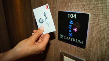 A hand holding a card labeled "CASTRUM" near a digital elevator panel displaying the number "104".